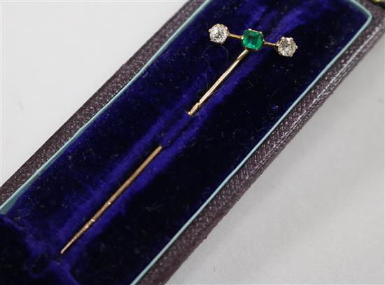 A diamond and emerald-set yellow metal stickpin, cased, 61mm.